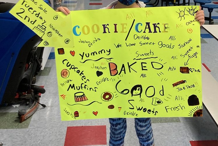 Child holding bake sale sign
